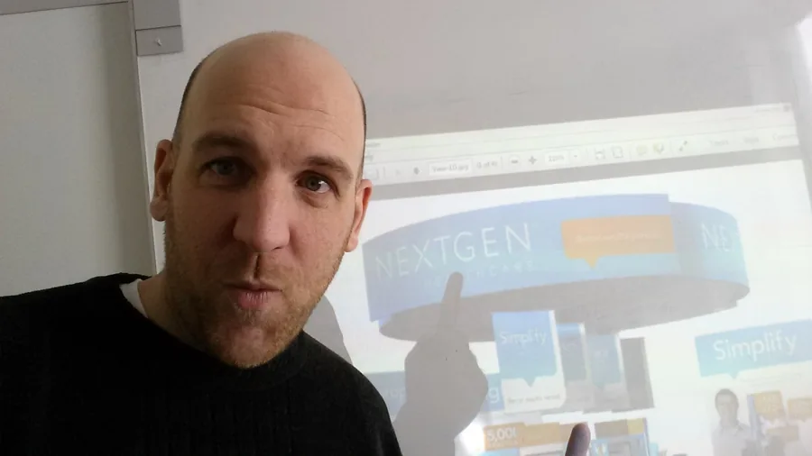 Jim Hollis pointing at a projected NextGen Healthcare trade show booth design